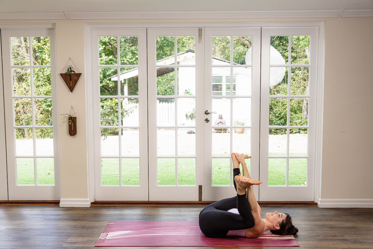 Young sporty attractive woman practicing yoga, doing Happy Baby exercise, Ananda  Balasana pose, working out, wearing sportswear, grey pants, top, indoor  close up, at yoga studio Stock Photo | Adobe Stock